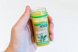 Livefresh Cannabis Shot frisch und kaltgepresst in der Hand gehalten vor weißem Hintergrund