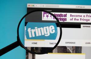 Logo des Fringe Festivals auf Computerbildschirm hervorgehoben durch Lupe