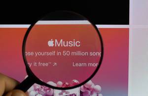 Logo und Schriftzug von Apple Music, mit Apfelsymbol, vergrößert durch eine Lupe dargestellt