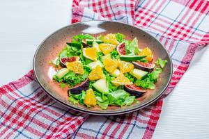 Low-calorie salad with fresh lettuce, oranges, figs and mango. The concept of vegetarianism, weight loss