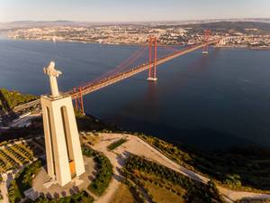 Luftaufnahme der Cristo Rei Statue über den Tajo auf Lissabon blickend mit Ponte 25 de Abril Brücke