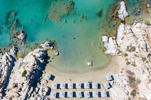 Luftaufnahme zeigt eine Frau die alleine im grünen Wasser des Mittelmeers schwimmt, in der Bucht am Strand Kolimbithres der griechischen Insel Paros