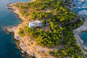 Luftaufnahme zeigt einen Leuchtturm auf dem abgelegen Teil der Insel Spetses, Griechenland, neben der Hafeneinfahrt