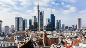 Luftbild zeigt Bauarbeiten mit Kränen vor den Hochhäusern einer deutschen Großstadt