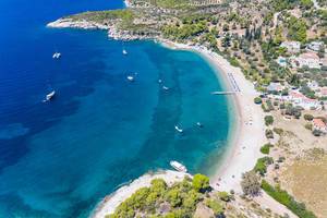 Luftbild zeigt das Meer in mehreren Blautönen und Urlauber auf Booten in der Ferienregion Agii Anargiri auf Spetses