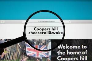 Lupe über Logo des Coopers Hill cheeseroll & wake, dem Käserennen in England, auf deren Website
