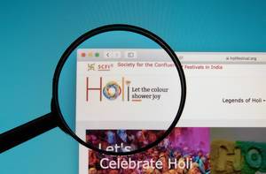 Lupe über Logo des Holi Festivals, dem auch „Fest der Farben“ genannten Hindufest aus Indien