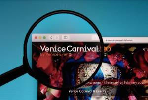 Lupe über Logo des Karnevals in Venedig auf der Website von Venice Carnival