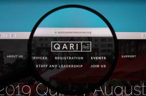 Lupe über PC-Bildschirm hebt QARI-Logo hervor auf Website von Quincy Asian Resources