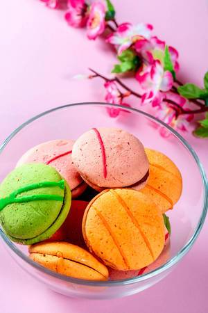 Macaroons cookies with flowers on pink background