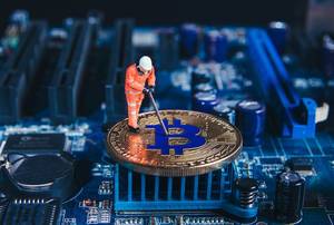 Macro miner figure working on a Bitcoin on computer motherboard