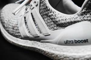 Macroaufnahme des Adidas Sneaker Ultra Boost, mit Strickmaterial, auf schwarzem Untergrund