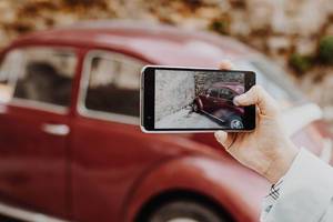 Mädchen fotografiert ein Oldtimer-Auto mit ihrem Smartphone