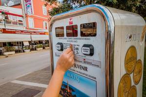 Mädchen kauft Souvenir am Automaten in Rovinj, Kroatien