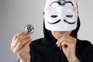 Mädchen mit weißer Maske hält eine Bitcoin Münze in der Hand