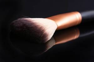 Makeup Brush above black reflective background