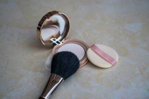 Makeup Brush laying on Powder Box with Mirror