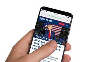 Male hands holding smartphone with an open Fox News website
