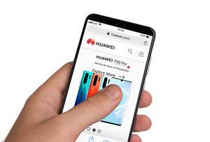 Male hands holding smartphone with an open Huawei website