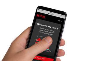 Male hands holding smartphone with an open Netflix application