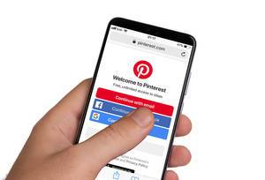 Male hands holding smartphone with an open Pinterest application