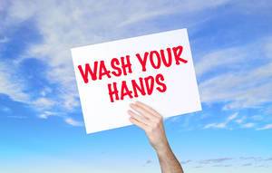 Man holding banner with Wash Your Hands text with blue sky background