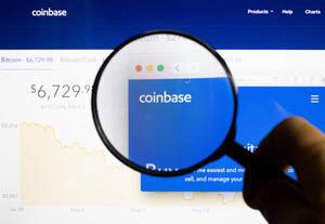 Man holding magnifying glass over Coinbase logo