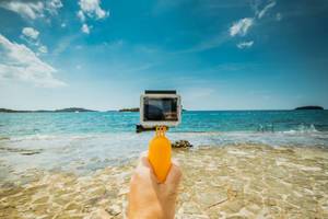 Man holding underwater camera (like GoPro) at the beach