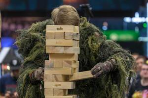Man in camouflage suit removes blocks from a Jenga tower at CaseKing booth