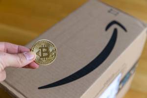 Man kann bei Amazon schon mit Bitcoin bezahlen - Hand hält Bitcoin-Münze aus Stahl und Edelmetall