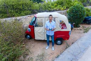 Man takes a drone selfie in front of a funny vehicle on greek Island Spetses