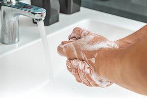 Man washing soapy hands in bathroom