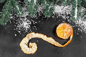 Mandarin with peeled peel on a dark background with snow (Flip 2019)