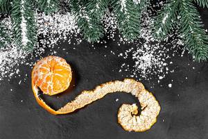 Mandarin with peeled peel on a dark background with snow