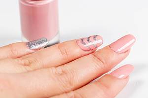 Maniküre: Nahaufnahme einer Frauenhand mit rosa Nagellack und silbernem Glitzer