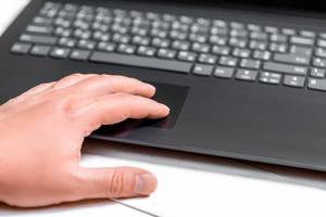 Mann arbeitet an schwarzem Laptop mit Hand auf Trackpad