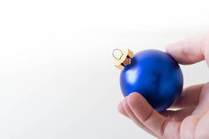 Mann hält blaue Weihnachtsbaumkugel in der Hand