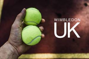 Mann hält in seiner Hand zwei Tennisbälle, neben der Aufschrift "Wimbledon UK", dem Namen der Tennis-Championships in London