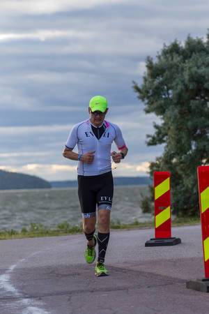 Mann läuft die Marathonetappe des Triathlonwettbewerbs Ironman 70.3 an der Küste von Lahti, Finnland