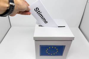 Mann nimmt von seinem Wahlrecht gebrauch und stimmt ab für die Europawahl, indem er seinen Wahlschein in die Urne steckt