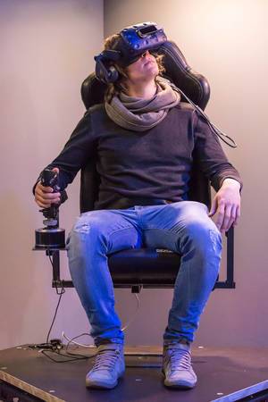 Mann simuliert mit Joystick und HTC Vive VR Brille einen Flug