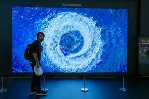 Mann steht zum Größenvergleich vor dem riesigen Samsung-Bildschirm "The Wall", mit LED Chip und Black Seal-Technologie