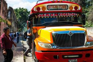 Mann steigt in typischen bunten Bus in Guatemala zwischen Antigua und Itzapa