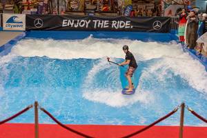 Mann surft vor Zuschauern auf stehender Welle (citywave) mit Slogan enjoy the ride