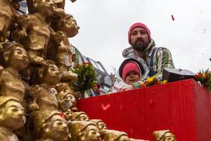 Mann und Kind in roter Mütze auf dem Wagen von Zugleiter Holger Kirsch beim Rosenmontagsumzug in Köln