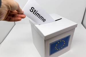 Männerhand bei der Stimmabgabe für die Wahl des Europäischen Parlaments, steckt den Stimmzettel in die Wahlurne