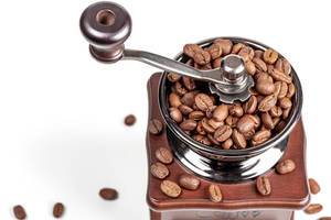 Manual coffee grinder with coffee beans on white background