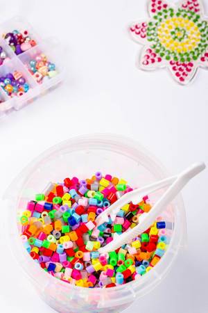 Many little beads with tweezers on white background