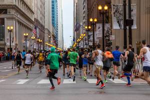 Marathon runners from behind, running over a crosswalk through the streets of Chicago