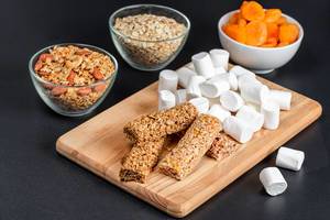 Marshmallows, granola bars, oatmeal and dried apricots on a dark background